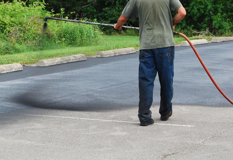 A team member from Driveways 2Day is applying asphalt sealcoating in Frederick, MD